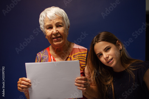 Aó com a neta e segurando uma folha de papel em branco para reclame photo