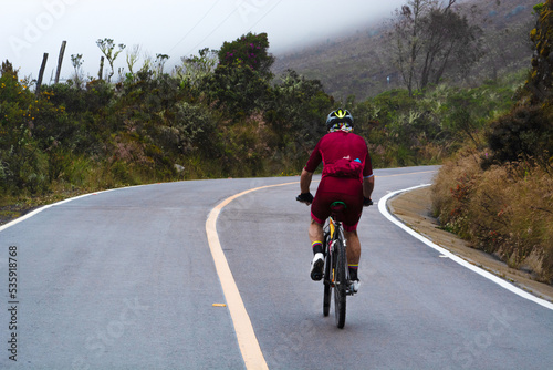 Cyclist man wearing red riding mountain bike on a path in the mountains. Background with a  fog and moorland vegetation