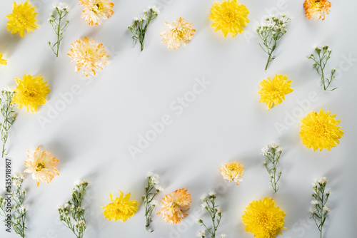 chrysanthemum and cutter flowers composition. Pattern and Frame made of various yellow or orange flowers and green leaves on white background. Flat lay, top view, copy space, spring, summer concept.