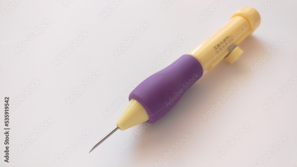 Purple and yellow punch needle pen on white background. Purple and yellow punch needle pen on white background.
