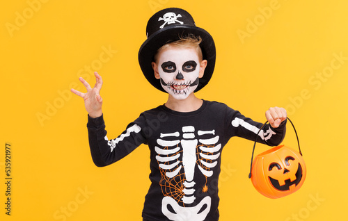Fotografia Happy cheerful boy in skeleton costume with  pumpkin  basket celebrates Hallowee
