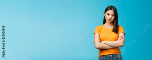 Serious-looking indifferent and upset intense asian woman brunette, cross arms chest look strict ignorant, pissed listening nonsense, annoyed stupid conversation, stand blue background
