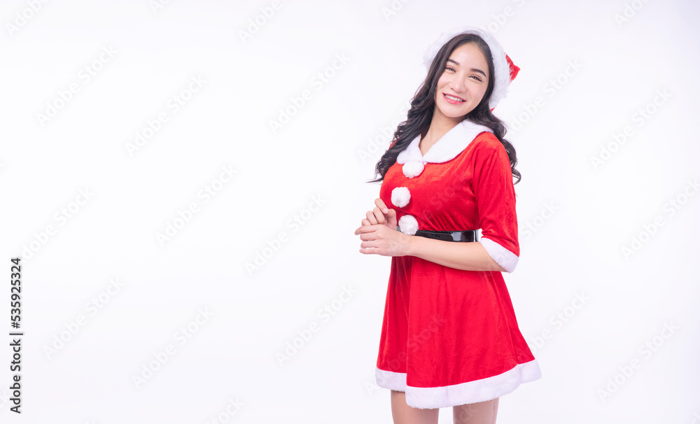 Cheerful asian Santa Claus dress with christmas hat standing holding hands on white background. Friendly Santa Claus young girl wear hat smiling look camera over isolated background. Merry christmas Cheerful asian Santa Claus dress with christmas hat standing holding hands on white background. Friendly Santa Claus young girl wear hat smiling look camera over isolated background. Merry christmas
