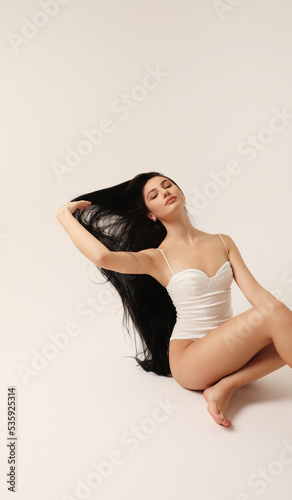 Beautiful young woman with long dark hair posing in the studio. Vertical.