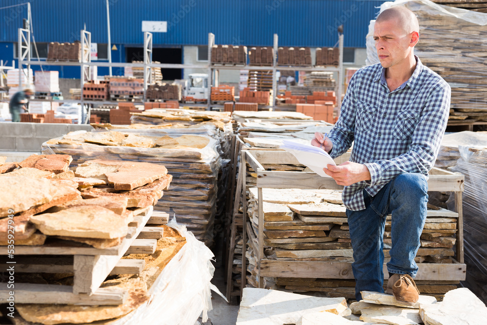 Man of a hardware store keeps records of natural stone tiles