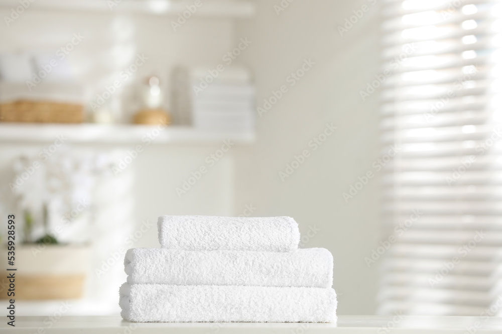 Stack of clean soft towels on white table indoors
