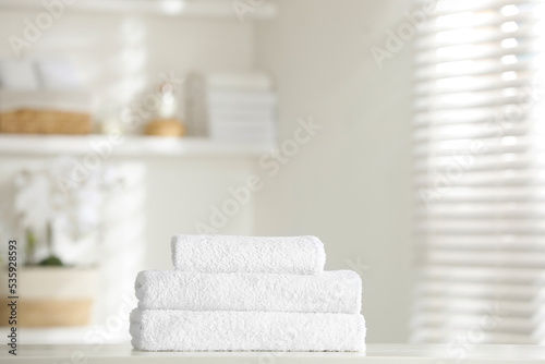 Stack of clean soft towels on white table indoors