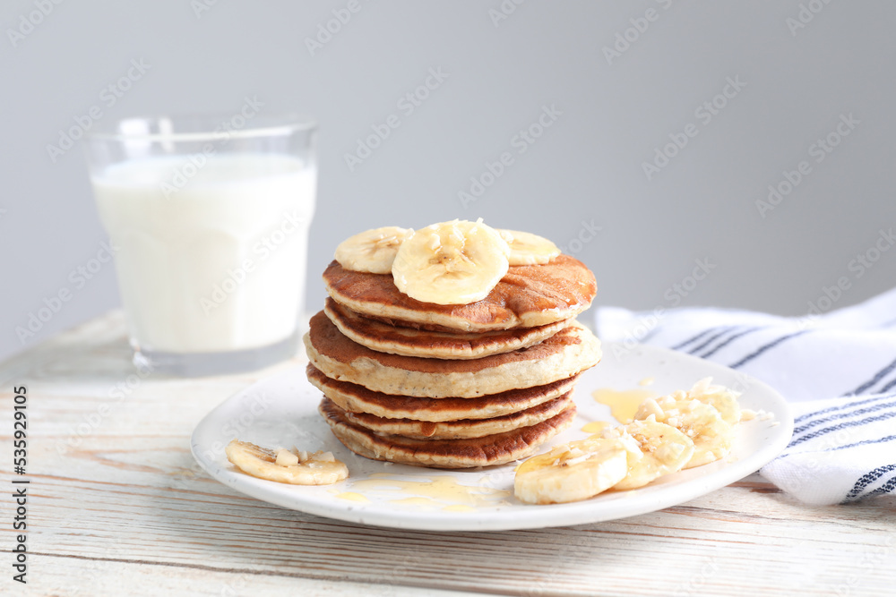 Plate of banana pancakes with honey on white wooden table Plate of banana pancakes with honey on white wooden table