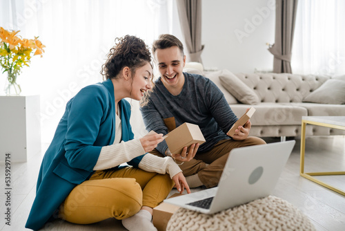 couple woman and man open presents and read card while on video call © Miljan Živković