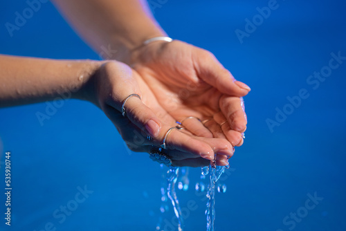 Clean water in woman hands. Palms with gypsy boho rings holding clear aqua. Freshness  purity  life-giving force  tropical background.