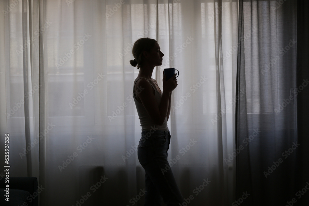 Woman drinking coffee next to the window