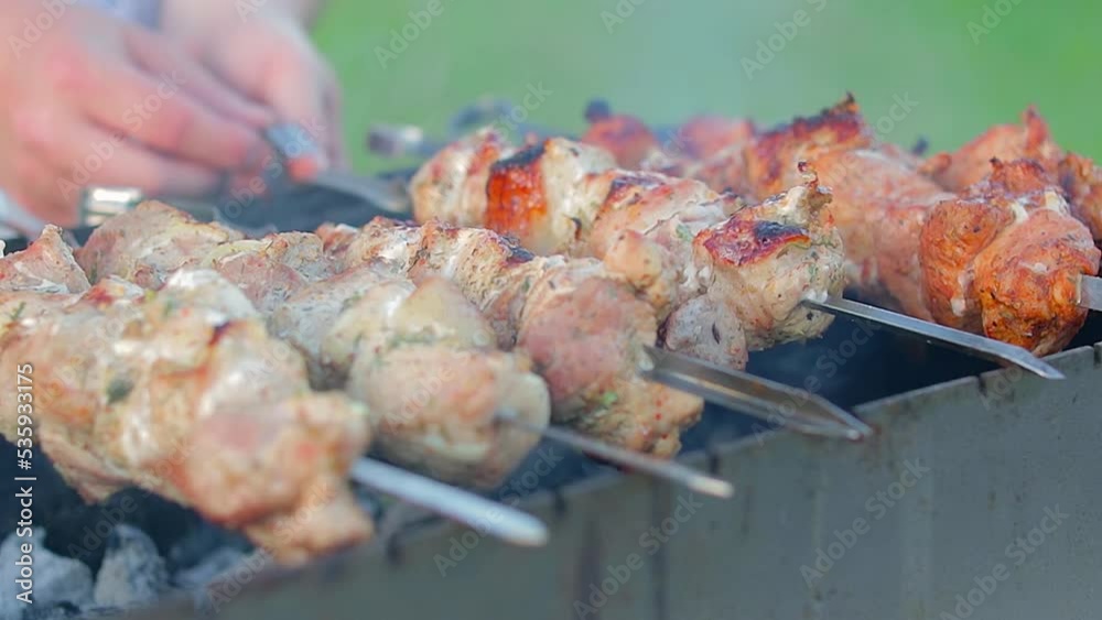 Man is Cooking Pork Barbecue in Summer in the Daytime Outdoors - Close-Up, Static Shot, Slow Motion. Turning Barbecue on Skewers. Hot Grilled Kebab on the Coals. Roasted or Grilled BBQ on a Skewer or Man is Cooking Pork Barbecue in Summer in the Daytime Outdoors - Close-Up, Static Shot, Slow Motion. Turning Barbecue on Skewers. Hot Grilled Kebab on the Coals. Roasted or Grilled BBQ on a Skewer or