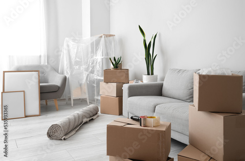 Cardboard boxes with sofa and armchair in living room on moving day