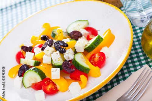 Traditional Greek salad with fresh vegetables, feta cheese and black olives served on white plate