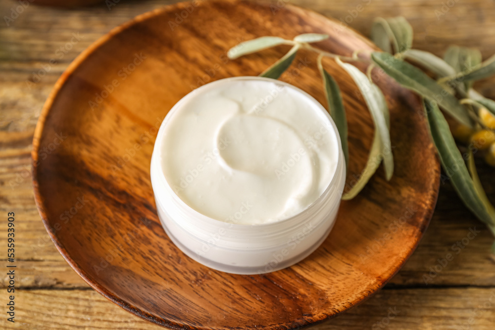 Plate with jar of natural olive cream on wooden table, closeup Plate with jar of natural olive cream on wooden table, closeup