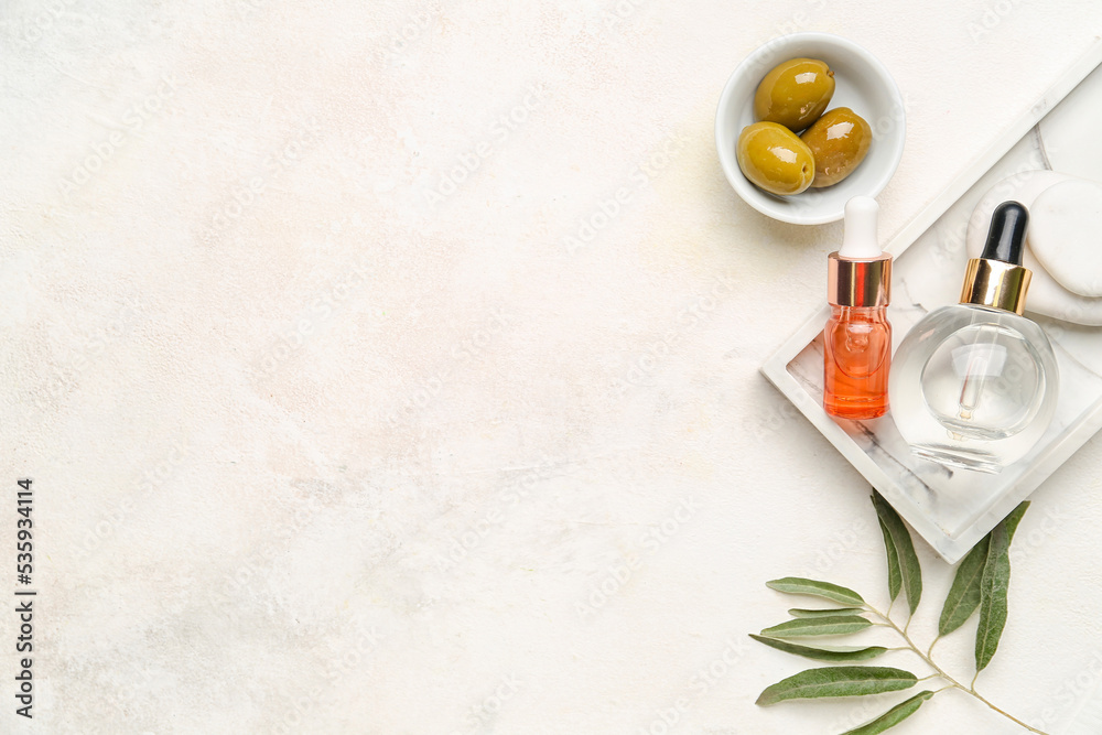 Bottles of essential olive oil on light background
