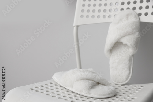 Soft white slippers on chair, space for text