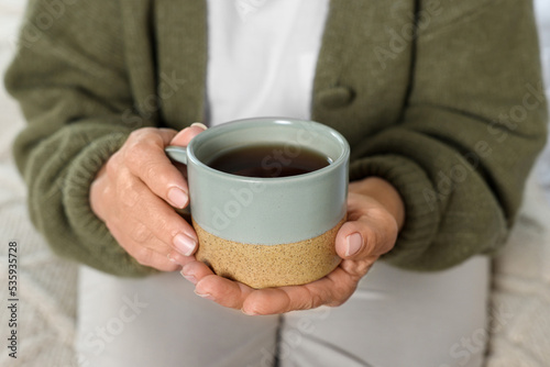 Elderly woman with cup of hot drink indoors  closeup. Home care service