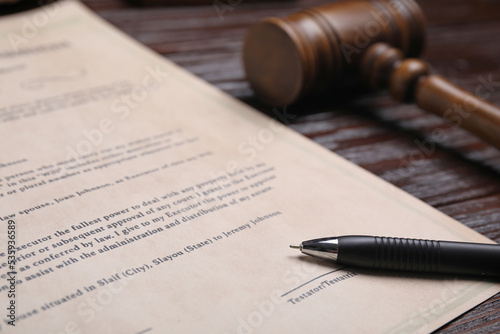 Last will and testament with pen near gavel on wooden table, closeup