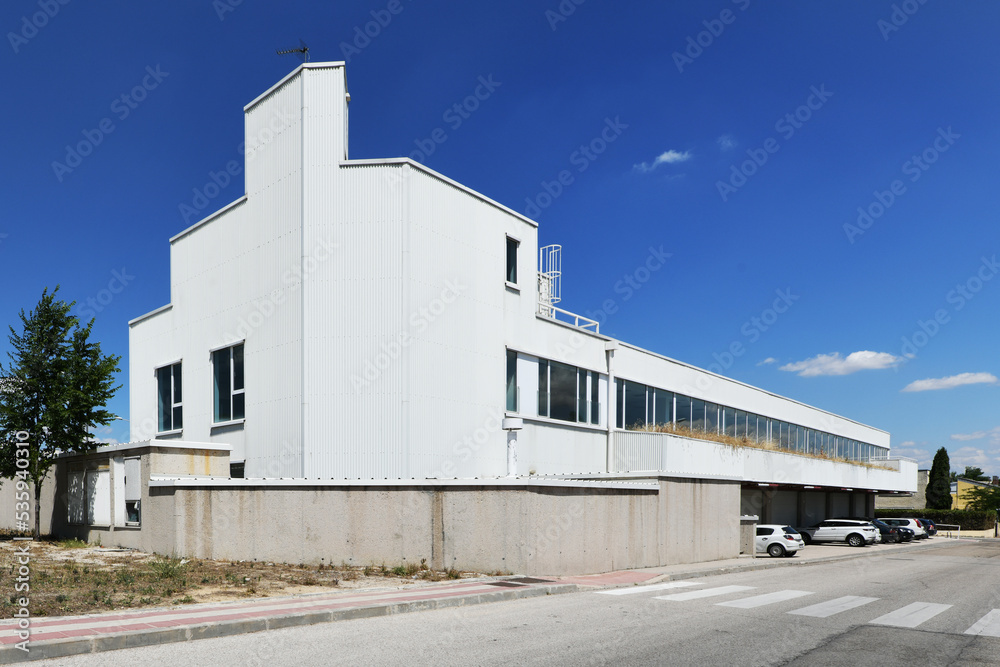 Facade of a lonely industrial building with white cladding, many windows and a clear blue sky Facade of a lonely industrial building with white cladding, many windows and a clear blue sky
