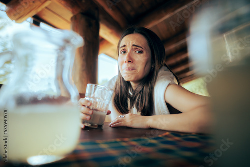 Expressive Woman Tasting a Sour Lemonade in a Restaurant. Funny girl drinking a citrus juice making a crinkled face
 photo