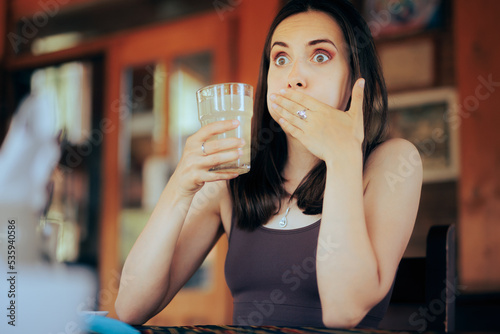 Woman Reacting after Drinking a Sour Beverage. Unhappy girl drinking a citrus beverage with a bad taste
 photo