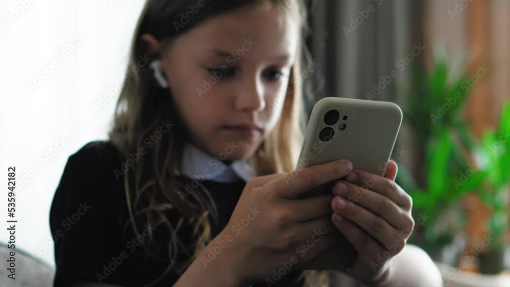 Close up of girl school child holding mobile, playing games, chatting online. Addicted kid girl using smartphone for fun and leisure. Close up of girl school child holding mobile, playing games, chatting online. Addicted kid girl using smartphone for fun and leisure.