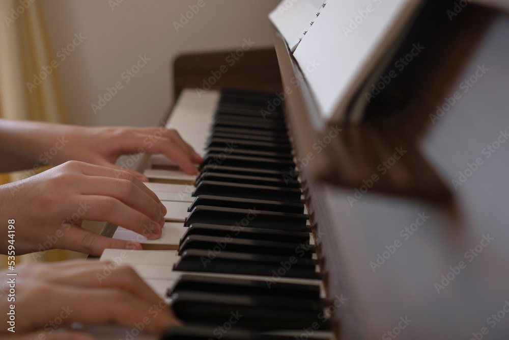 Fototapeta premium Two people playing the piece for piano duet in the room. 部屋のピアノで連弾する二人