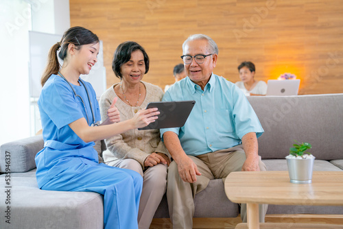 ฺBeautiful Asian nurse or doctor use tablet to consult and give assistant to couple senior man and woman in living room of clinic or hospital in senior healthcare center.