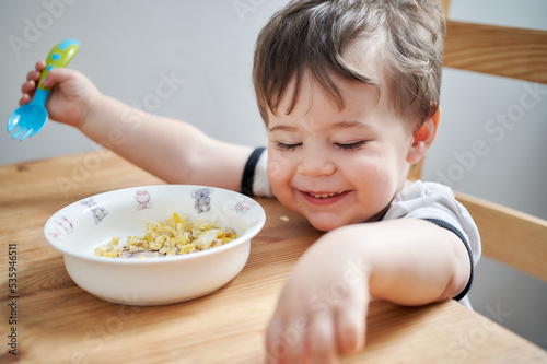toddler eating eggs for breakfast and fooling around photo