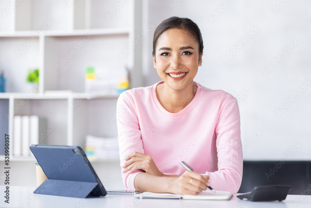 Asian Woman using digital tablet while sitting at home workplace, Asian Female designer sketching on a graphic tablet while working at home. Asian Woman using digital tablet while sitting at home workplace, Asian Female designer sketching on a graphic tablet while working at home.