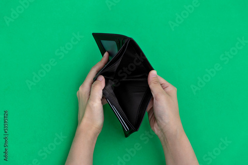Foto Woman hand open an empty wallet on green background