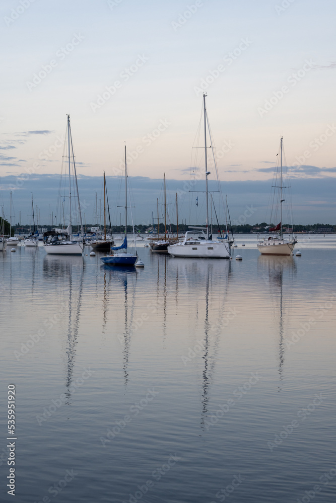Sailboats in Dinner Key anchorage reflected in calm water of Biscayne Bay in Miami, Florida.