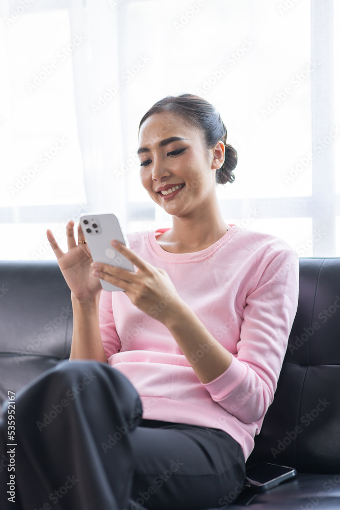 Beautiful Young Asian woman using smartphone on sofa at home, shopping online with internet in happy mood and Relax part time concept Beautiful Young Asian woman using smartphone on sofa at home, shopping online with internet in happy mood and Relax part time concept