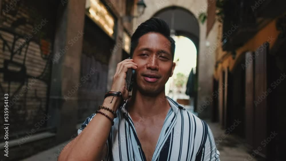 Young man tourist walks along narrow street of the old city and talks on mobile phone Young man tourist walks along narrow street of the old city and talks on mobile phone