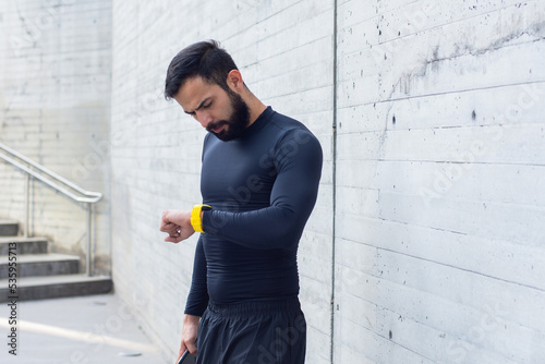 Young athlete looks his watch on the street