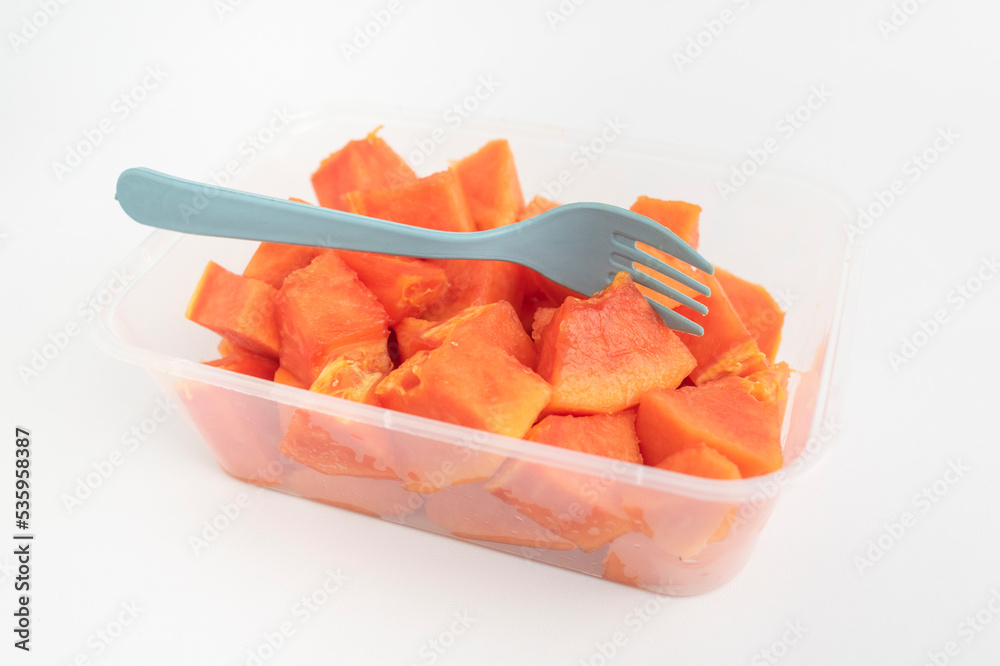 close up of fresh orange papaya with plastic fork on plastic box isolated on white background close up of fresh orange papaya with plastic fork on plastic box isolated on white background