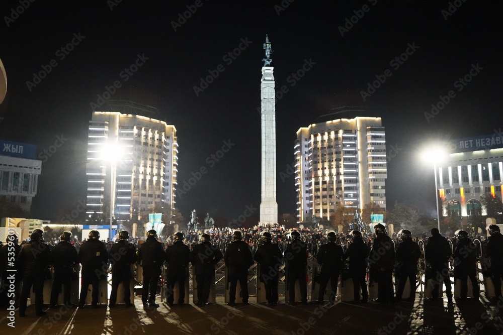 Almaty, Kazakhstan - 01.04.2022 : The police are lined up in front of the protesters on the central square near the city hall. Mass riots. Almaty, Kazakhstan - 01.04.2022 : The police are lined up in front of the protesters on the central square near the city hall. Mass riots.