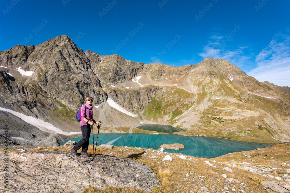 The girl stands against the backdrop of mountain peaks and a blue lake. Beautiful mountain landscape for vacation, travel and healthy lifestyle