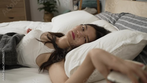 closeup view of an asian female waking to the alarm triggered on her phone is turning it off and checking time in the morning on bed in the bedroom at home.