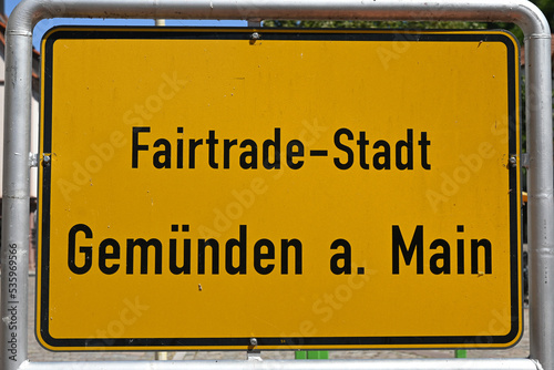 gelbes Ortsschild von Gemünden am Main, Fairtrade-Stadt, Main-Spessart in Unterfranken, Franken,  Bayern Deutschland bei blauem Himmel photo