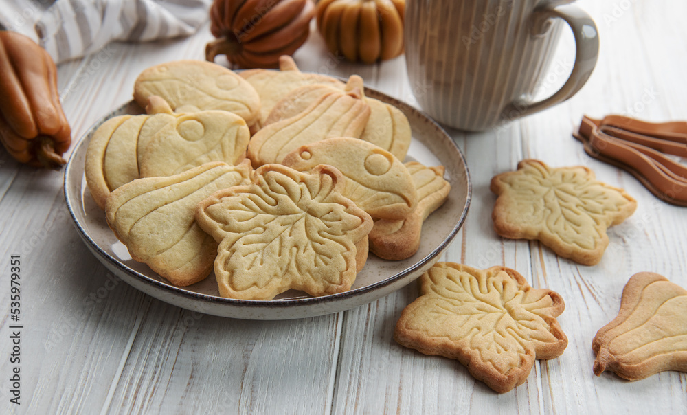 Cookies shaped like pumpkin and leaves on rustic wood background