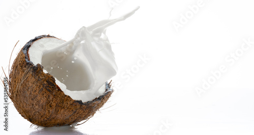 Half coconut with milk splash on white background