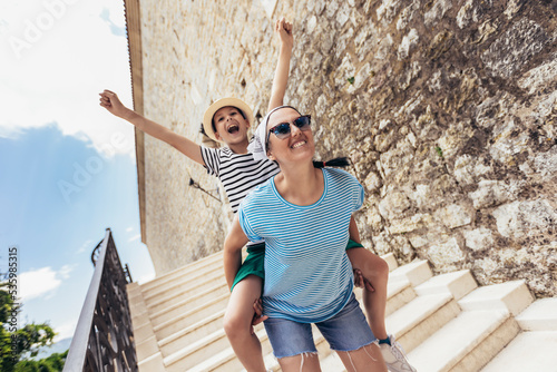 Fotografie Mother and son enjoying piggyback ride during sightseeing of the old town