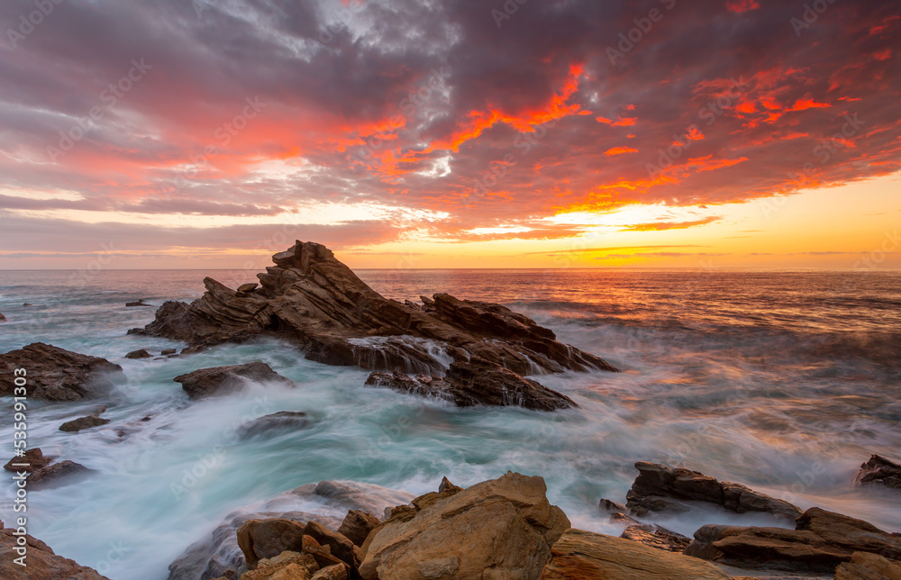 Sunrise over the ocean and rocky beach foreground