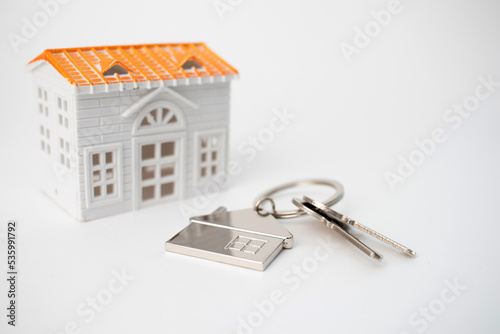 Real estate concept. House model and keys with a keychain in the shape of a house © epovdima