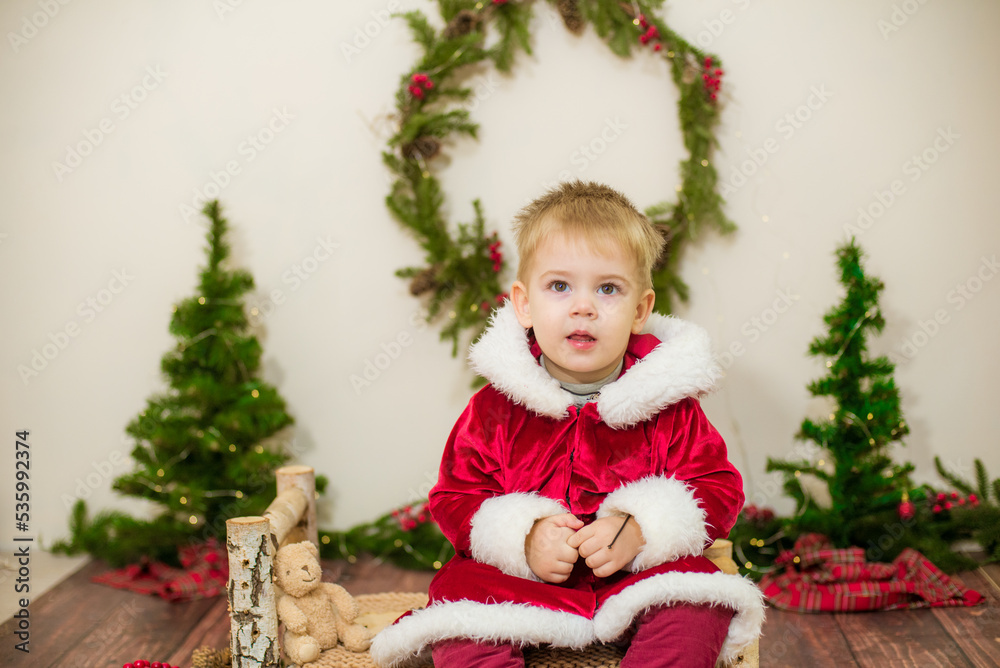 Little cute boy dressed as Santa Claus in a room decorated for Christmas. Christmas and children Little cute boy dressed as Santa Claus in a room decorated for Christmas. Christmas and children