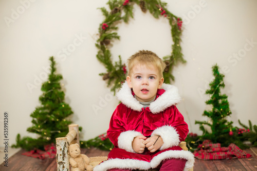 Little cute boy dressed as Santa Claus in a room decorated for Christmas. Christmas and children © capable97