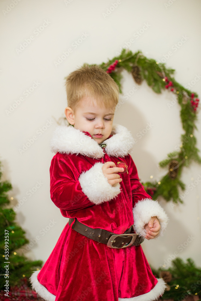 Little cute boy dressed as Santa Claus in a room decorated for Christmas. Christmas and children Little cute boy dressed as Santa Claus in a room decorated for Christmas. Christmas and children
