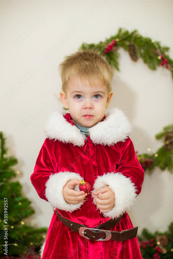Little cute boy dressed as Santa Claus in a room decorated for Christmas. Christmas and children Little cute boy dressed as Santa Claus in a room decorated for Christmas. Christmas and children